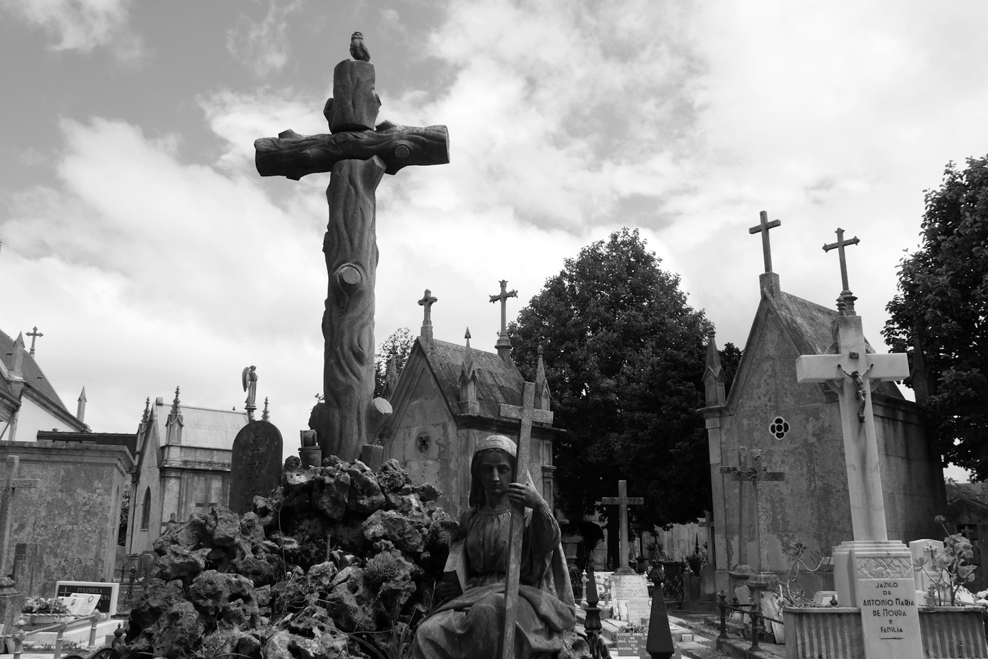Stone statues and weathered monuments stand in a historic cemetery.