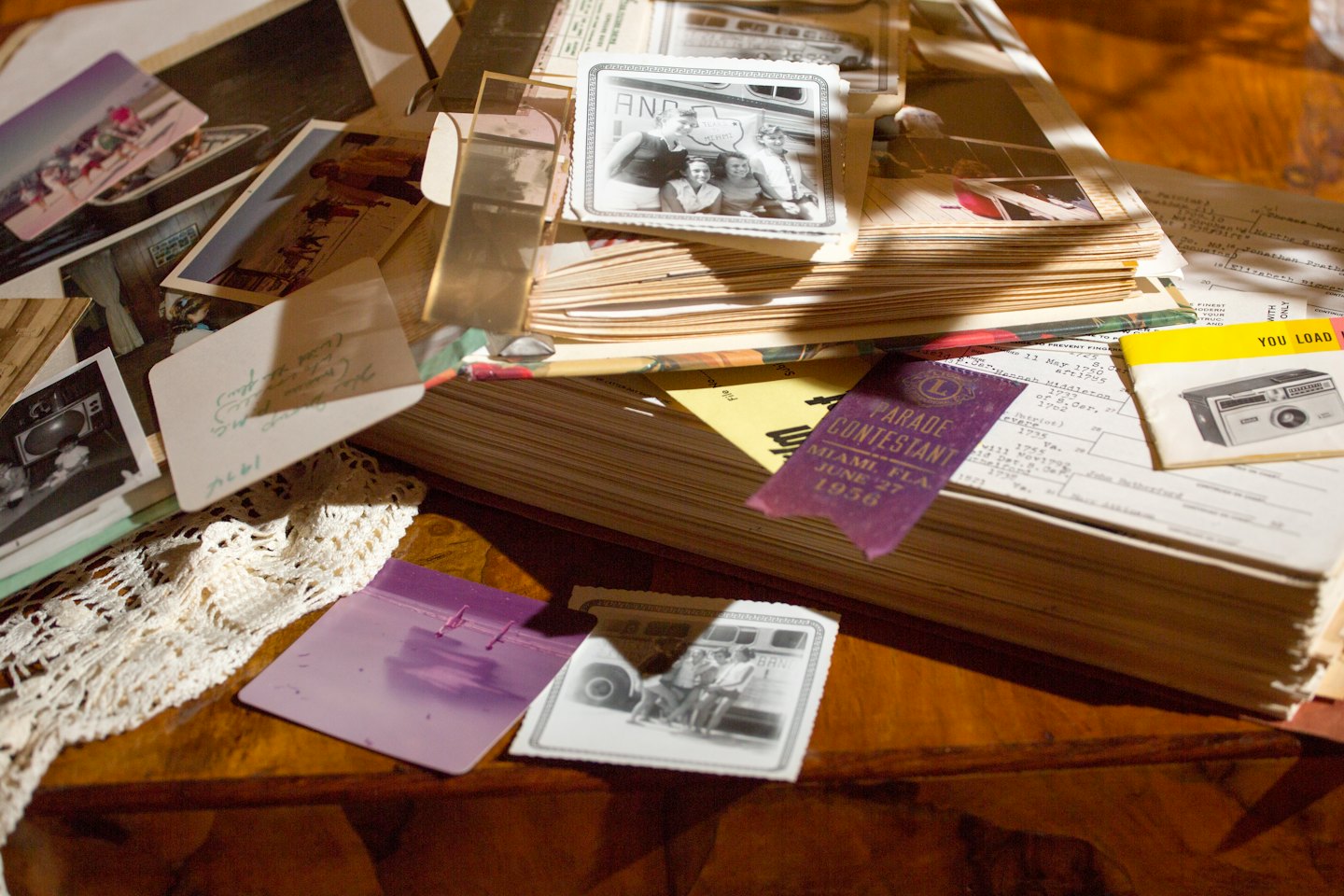 Vintage photographs and documents are spread across a wooden table.