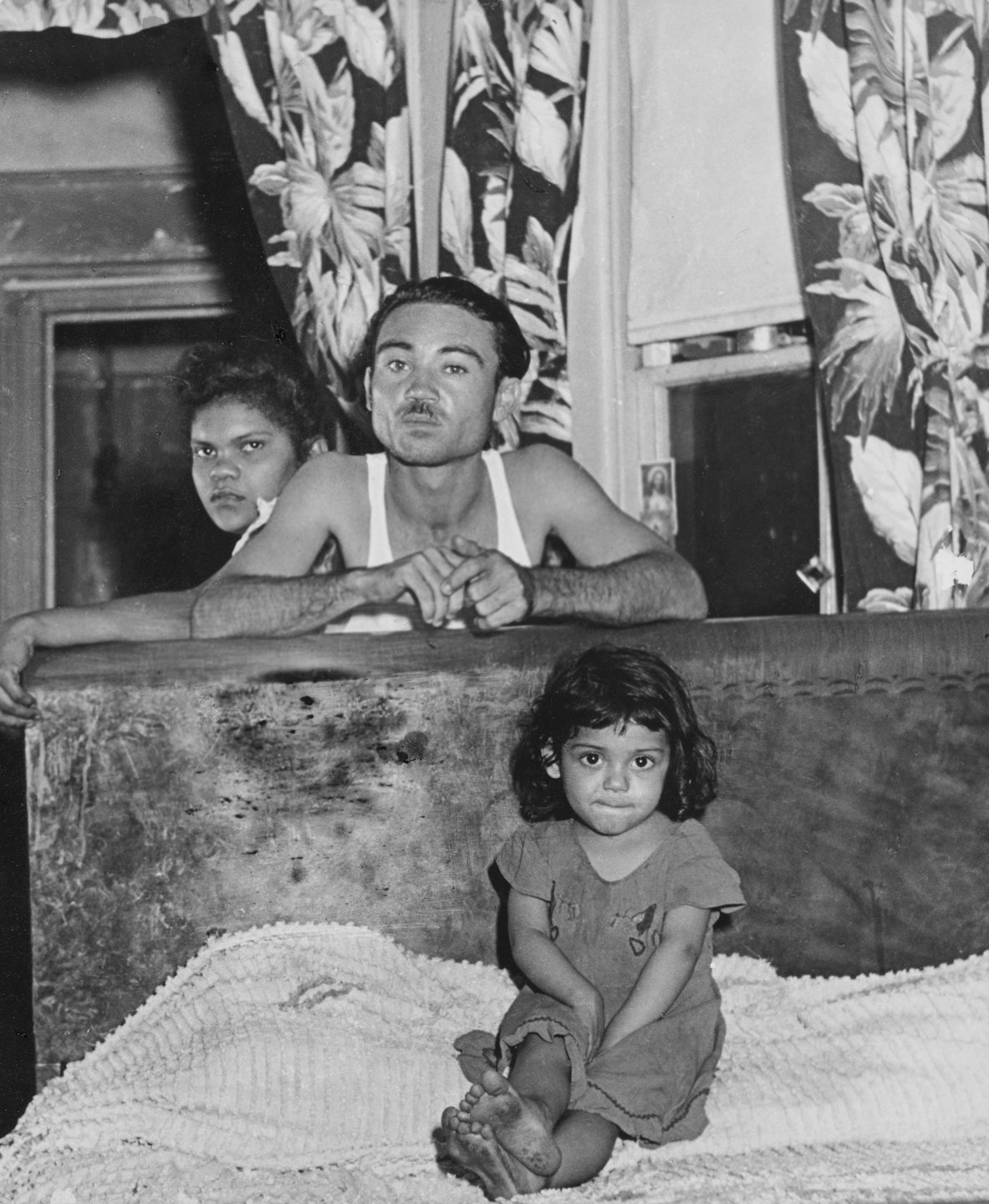 Three family members pose together behind a wooden chest.